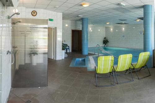 a pool room with yellow chairs and a swimming pool at Bagoly Fogadó in Gyömrő