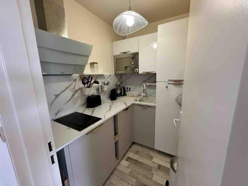 une cuisine blanche avec un évier et un comptoir dans l'établissement Bel Cabourg - Proche plage & Centre Cabourg, à Cabourg