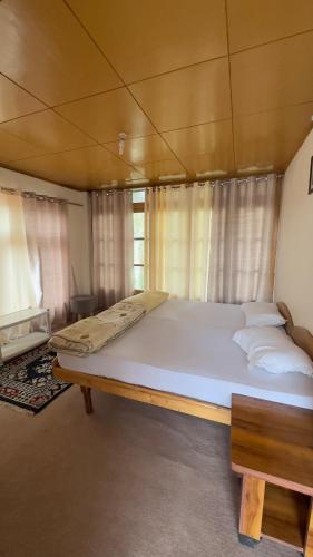 a large white bed in a room with curtains at Thangkop House in Leh