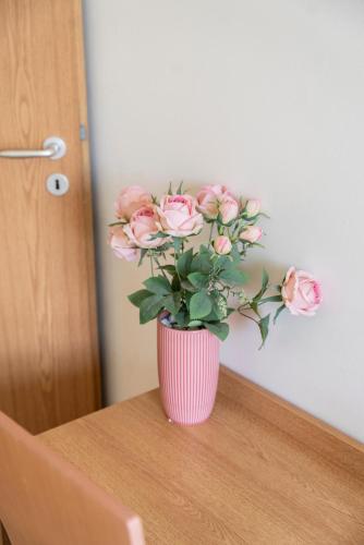 a pink vase with pink roses in it on a table at Bagoly Fogadó in Gyömrő
