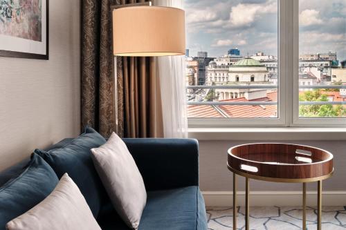 a living room with a blue couch and a window at Sheraton Grand Warsaw in Warsaw