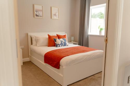 a bedroom with a white bed with orange and blue pillows at Fieldside Cottage in Scarborough