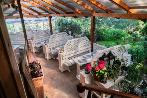 a row of white benches on a patio with flowers at Bagoly Fogadó in Gyömrő