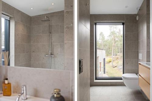 a bathroom with a shower and a sink and a toilet at Exklusiv villa med pool & fri havsutsikt in Sommarbo