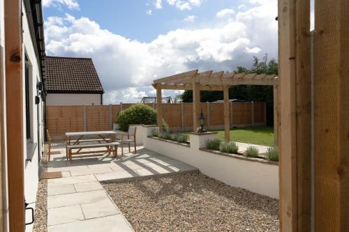 a patio with a picnic table and a wooden pergola at Fieldside Cottage in Scarborough