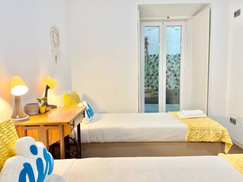 a bedroom with two beds and a desk and a window at PicaPau 59105AL in Lisbon