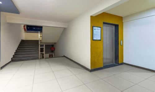a hallway with a staircase and a yellow door at Treebo KBC in Ahmedabad