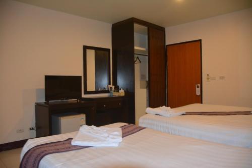 a hotel room with two beds and a desk and a mirror at Patong Moon Inn Residence in Patong Beach