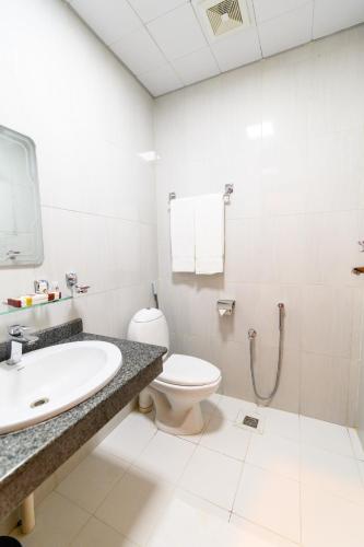 a white bathroom with a toilet and a sink at Hotel One Mansehra in Mānsehra