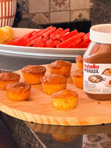 a wooden cutting board with muffins and a plate of carrots at Malie Hotel in Águas Belas