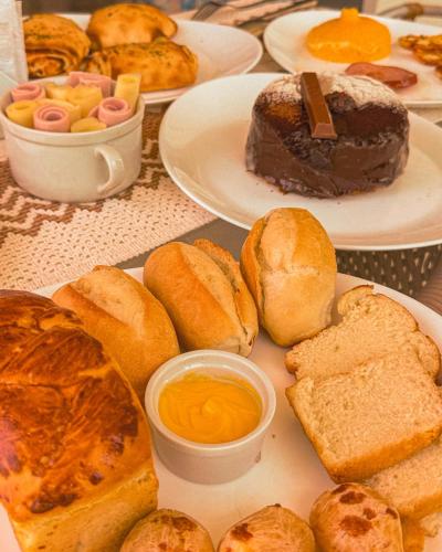 a table topped with plates of bread and pastries at Malie Hotel in Águas Belas