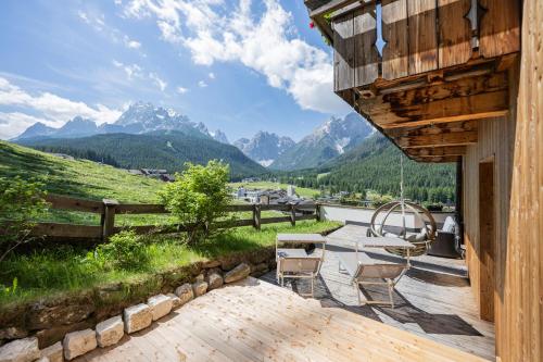 a deck with a table and chairs and mountains at Berghotel - Sexten in Sesto