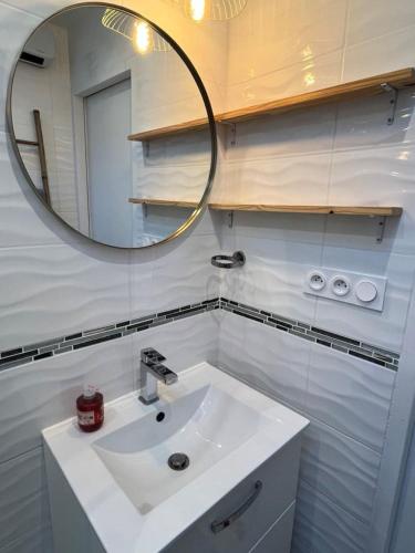 une salle de bain avec un lavabo blanc et un miroir dans l'établissement Maisonnette quartier Arago, à Les Sables-dʼOlonne