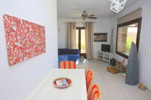a living room with a couch and a table with chairs at Pi Beach house- Kea Villa Rent - Kastellakia Bay Villas in Pisses