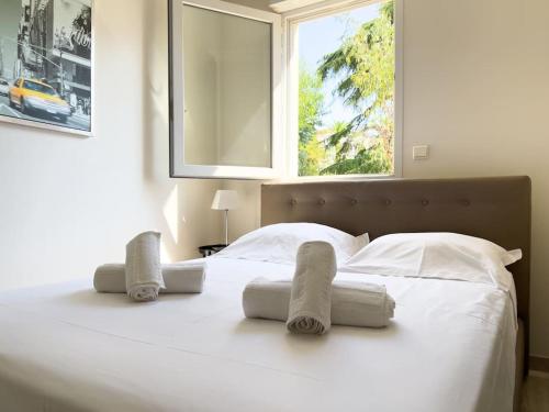 une chambre avec un lit blanc avec des serviettes dessus dans l'établissement Charmant Studio avec terrasse et vue arborée, à Cannes