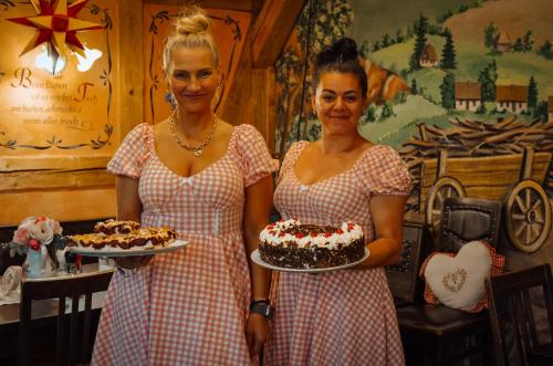 two women in dresses holding a cake at Pension Zum Erzgebirge in Kurort Altenberg