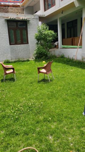 two chairs sitting in the grass in front of a house at Ultar House in Karimabad Hunza