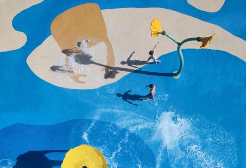 a painting of people on a surfboard in the water at Ikos Dassia in Dassia