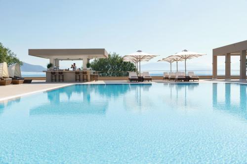 a large swimming pool with chairs and umbrellas at Ikos Dassia in Dassia
