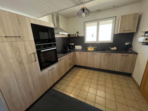 une grande cuisine avec des placards en bois et une fenêtre dans l'établissement Villa calme avec jardin clos, à 800m de la plage et 600m des commerces à Brétignolles-sur-Mer - FR-1-324-198, à Bretignolles-sur-Mer