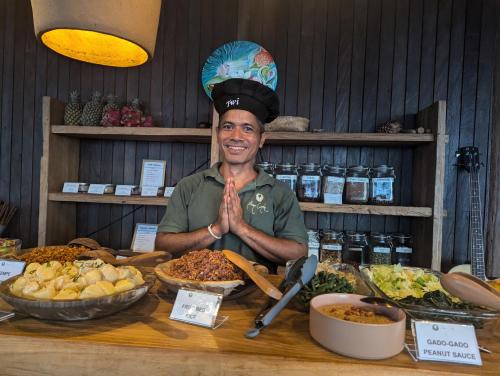 a man standing in front of a table with food at Bumi Cinta Bali in Tejakula