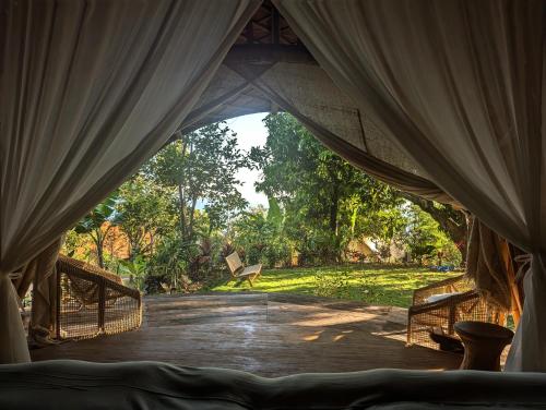 a tent with curtains and a bench in a park at Bumi Cinta Bali in Tejakula