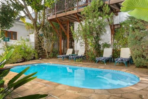 a swimming pool with chairs and a deck at Gable Manor by Neighbourgood in Franschhoek