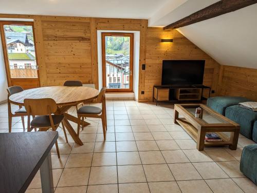 un salon avec une table et une télévision dans l'établissement Beau Duplex 100m2 au cœur de Beaufort - avec vue montagnes, à Beaufort