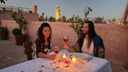 a man and woman sitting at a table with wine glasses at Riad Atrium & Spa in Marrakech
