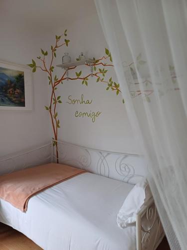 a bedroom with a bed with a tree on the wall at TEA HOUSE GERÊS in Geres