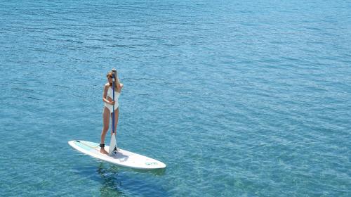 a woman standing on a surfboard in the water at Ikos Dassia in Dassia