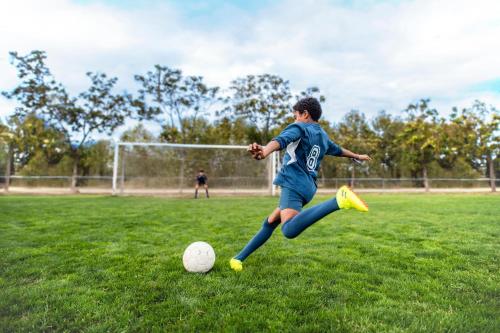 a young boy kicking a soccer ball on a field at Ikos Dassia in Dassia