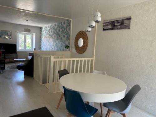 un salon avec une table et des chaises blanches dans l'établissement Appartement lumineux et agréable avec jardin, à Bavilliers
