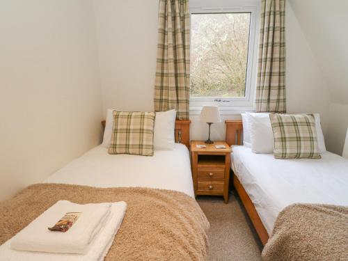 two twin beds in a room with a window at Lodge 2 - Inglewood Lodge in Spean Bridge