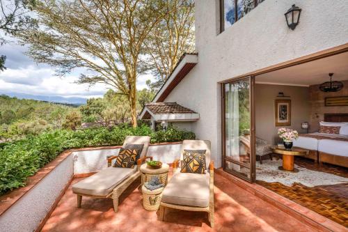 a patio with two chairs and a bed at Fairmont Mount Kenya Safari Club in Nanyuki