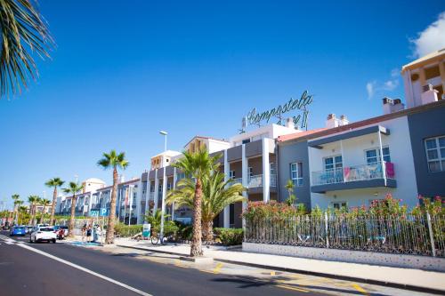 a street in front of a building with palm trees at Coral Compostela Beach Golf in Playa de las Americas