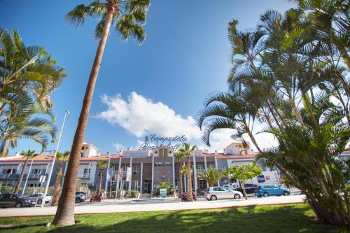 a street with palm trees in front of a building at Coral Compostela Beach Golf in Playa de las Americas