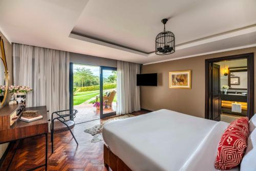 a bedroom with a large white bed and a desk at Fairmont Mount Kenya Safari Club in Nanyuki