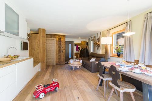 een keuken en een woonkamer met een rode speelgoedauto op de vloer bij Chalet Da Mont in Selva di Val Gardena