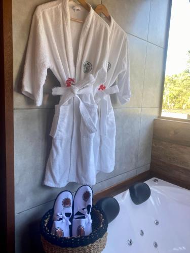 a bathroom with a robe and shoes on a tub at Chalés do Figa in Visconde De Maua