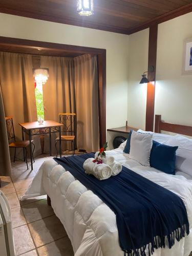 a bedroom with a large bed with a blue blanket at Chalés do Figa in Visconde De Maua