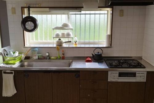 a kitchen with a sink and a stove and a window at はうす41マイルズ in Katakai