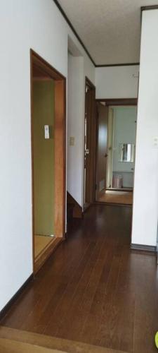 an empty room with two doors and a wooden floor at はうす41マイルズ in Katakai