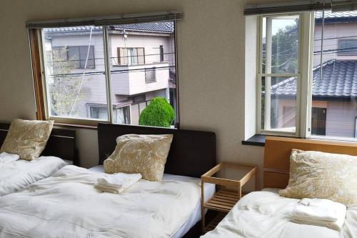 two beds in a room with two windows at はうす41マイルズ in Katakai