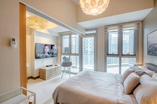 a bedroom with a bed and a flat screen tv at Uptown BGC in Manila