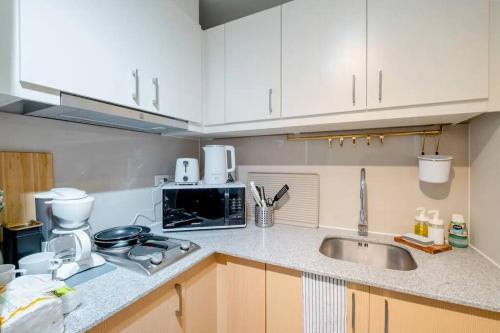 a kitchen with a sink and a microwave at Uptown BGC in Manila