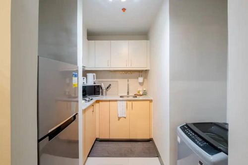 a small kitchen with white cabinets and a refrigerator at Uptown BGC in Manila
