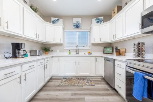 a white kitchen with white cabinets and a sink at Luxury, Style and Comfort 4 Bathrooms 21 in Ridgecrest
