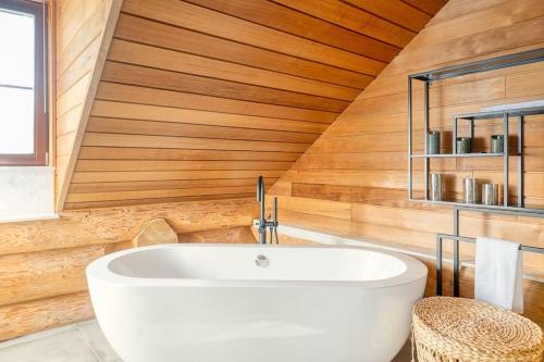 a bathroom with a white tub in a wooden wall at Cozy 4-Bedroom Chalet with Outdoor Spa in Zottegem in Zottegem