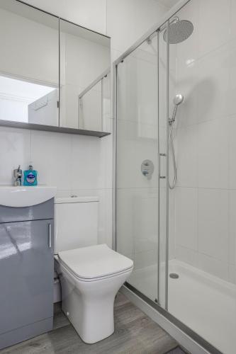 a white bathroom with a toilet and a shower at Bright 2-Bed in Wimbledon - 3 min Walk to Tube in London